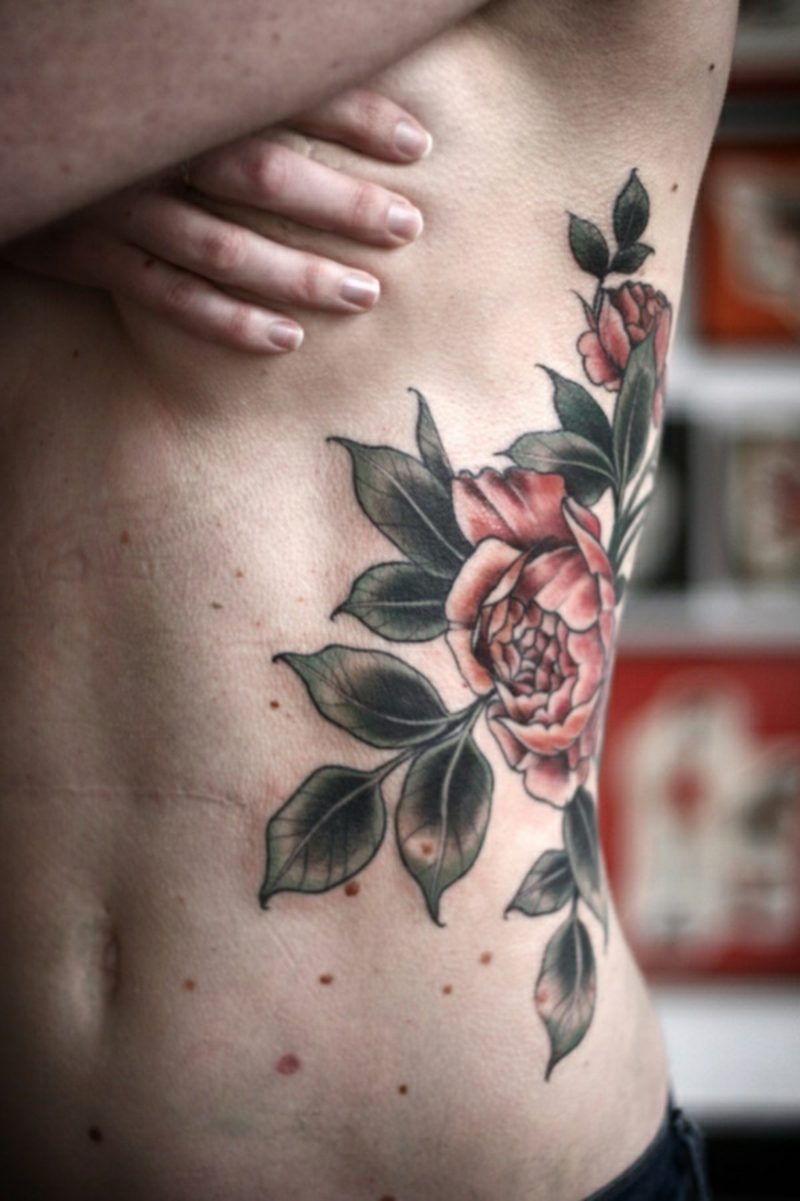 Tattoo av Hawaiian Flower Rut som går gjennom magen av denne jenta