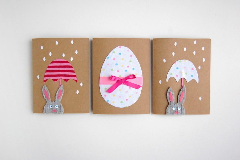 การ์ดอีสเตอร์บนกระดาษแข็งที่มีไข่และกระต่ายที่มีร่มและริบบิ้นสีชมพู