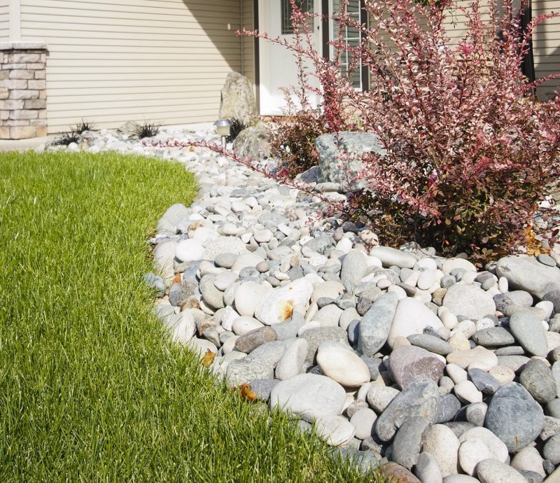 Lägg ut en säng av stenar för att skapa en separation mellan vägen till huset och gräset