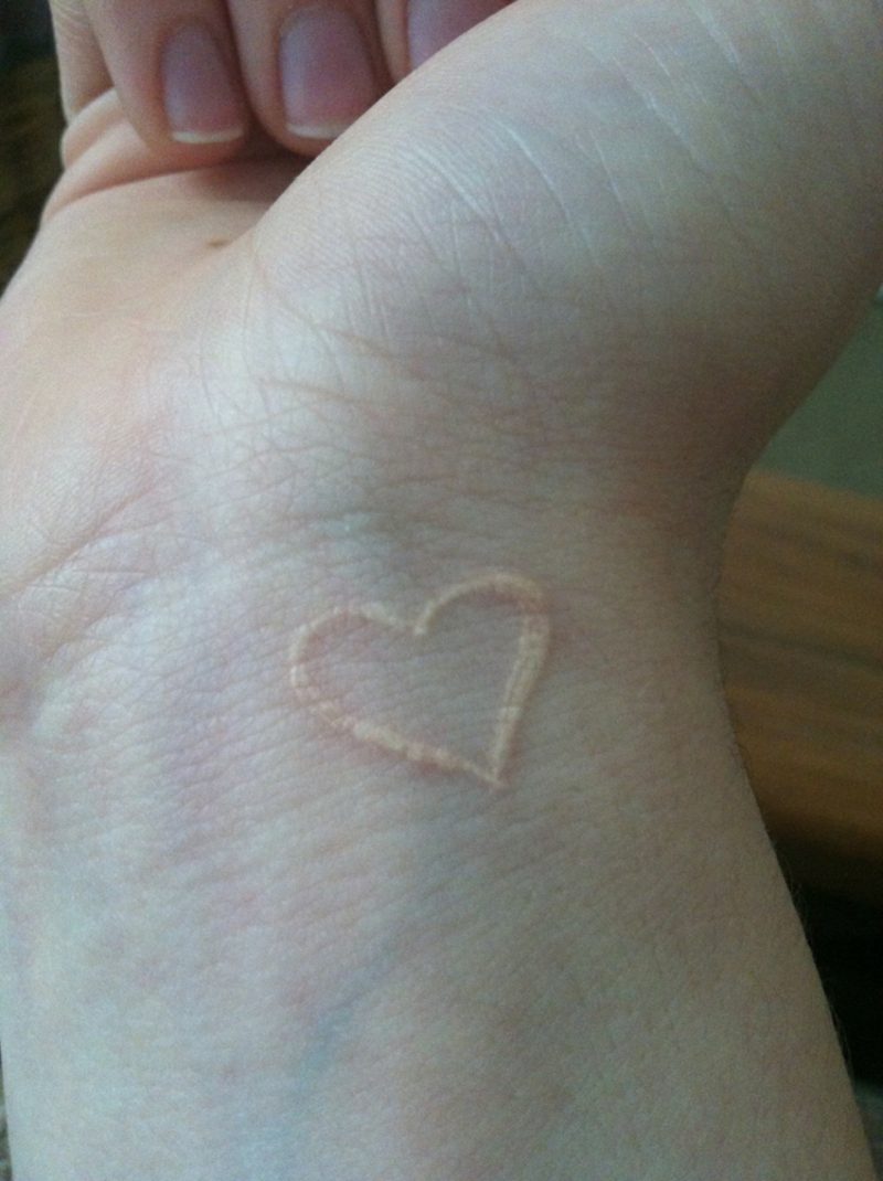 vit bläck tatuering hjärta handleden