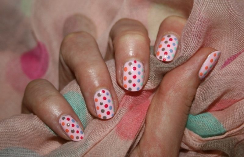 Fingernails med färgade prickar av rosa nagellack