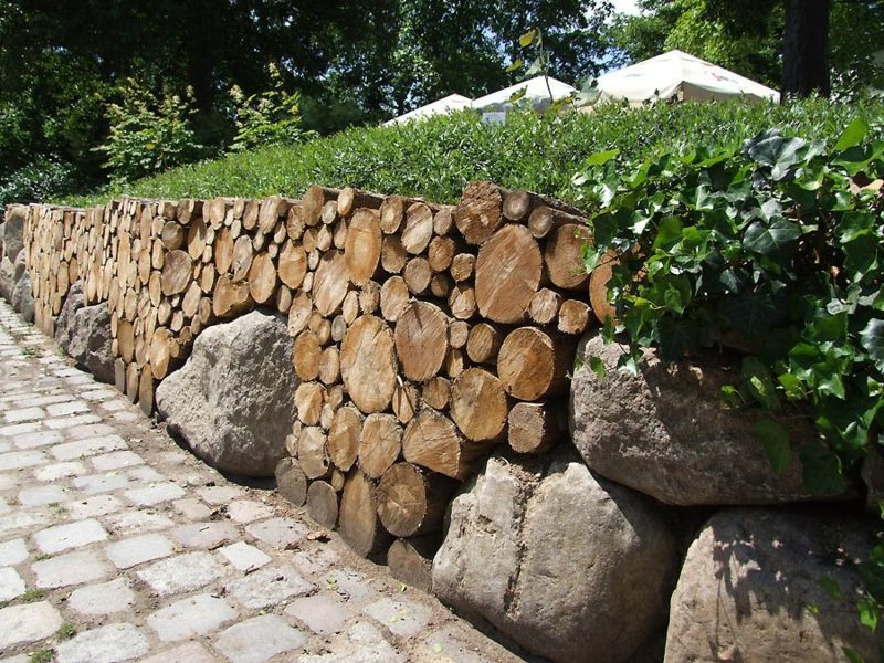 Parede de jardim interessante de madeira e pedras maciças