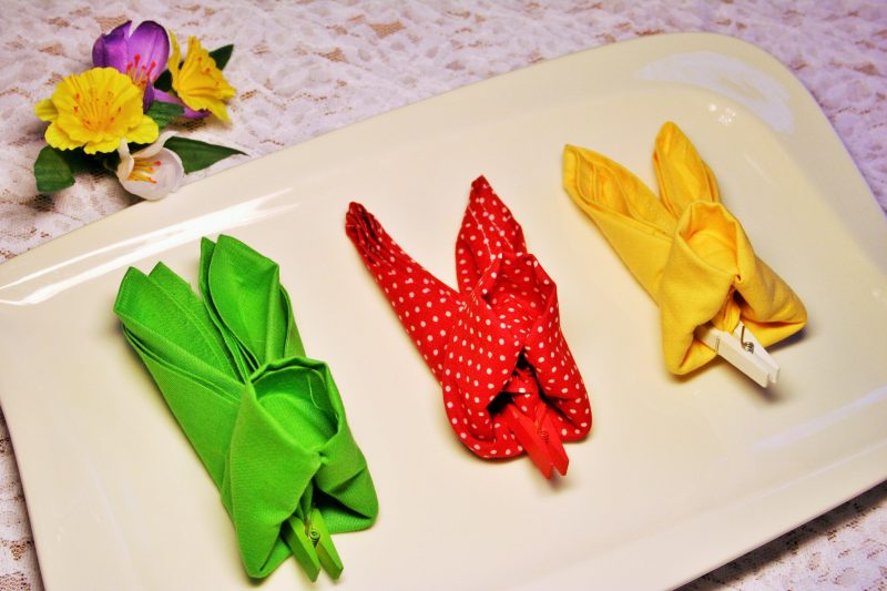 Färgglada servetter viks i en påskkanin i olika ljusa färger som en accent på bordet