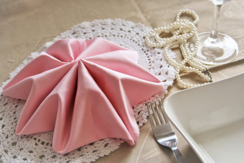 ピンクのナプキン折り畳み式の指使いのビーズとの組み合わせで控えめな雰囲気を演出